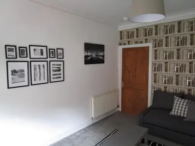 a living room with a couch and a wall of books at Westend Glasgow Apartment in Glasgow