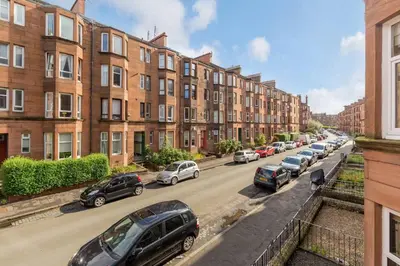 a row of cars parked on a street with buildings at Westend Glasgow Apartment in Glasgow