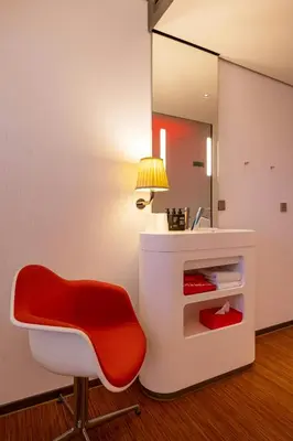 a red chair in a room with a mirror at citizenM Glasgow in Glasgow