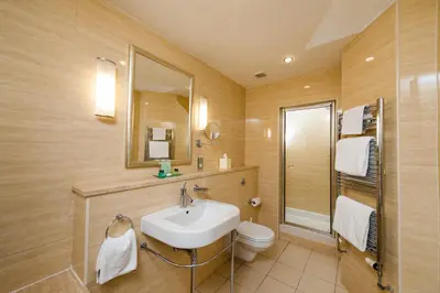 a bathroom with a sink and a toilet and a mirror at Piersland House in Troon