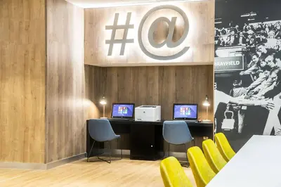 a room with two computers on a desk with yellow chairs at Courtyard by Marriott Edinburgh West in Edinburgh