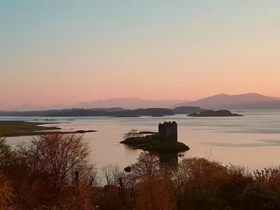 a castle on an island in the water at sunset at Appin Bay View in Appin