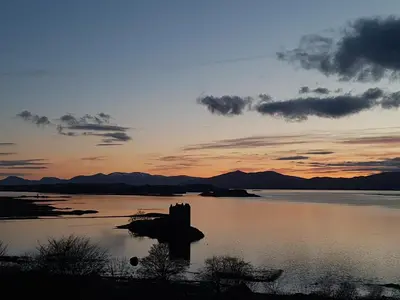 a sunset over a body of water with a rock in the middle at Appin Bay View in Appin