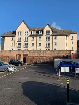 a large building with cars parked in a parking lot at 1/5 Lismore House in Oban