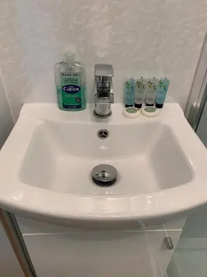 a white sink with a bottle of mouthwash and a glass at 1/5 Lismore House in Oban