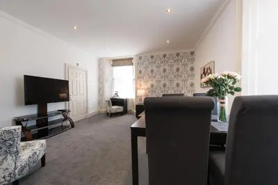 a living room with a television and a table with chairs at Royal Princes Suites in Edinburgh