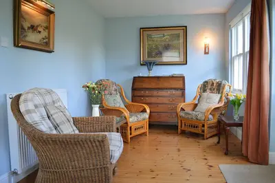 a living room with three chairs and a dresser at Shelduck Cottage in Feorlean
