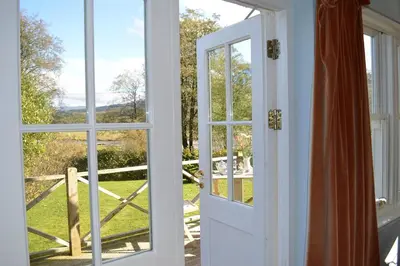 an open door with a view of a yard at Shelduck Cottage in Feorlean