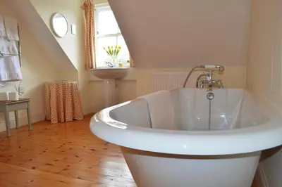 a bathroom with a bath tub and a window at Shelduck Cottage in Feorlean