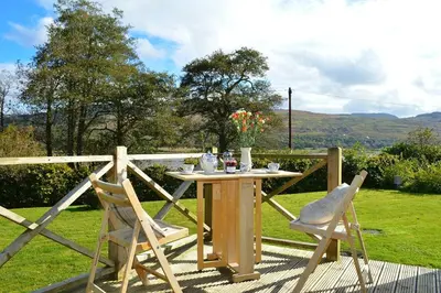 a table and two chairs sitting on a deck at Shelduck Cottage in Feorlean