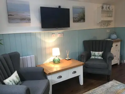 a living room with two chairs and a table with a tv at Angel Cottage in Drymen