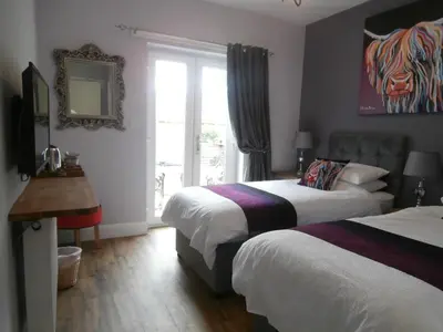 a hotel room with two beds and a window at Angel Cottage in Drymen