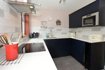 a kitchen with black cabinets and a red trash can at Birch Cottage in Blairmore