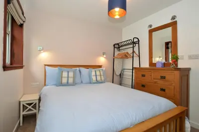 a bedroom with a bed and a dresser and a mirror at Birch Cottage in Blairmore