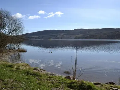 a lake with two ducks swimming in the water at Craigdarroch Cottage in Strathyre