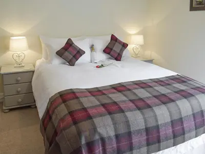 a bedroom with a large bed with a plaid blanket at Sandhaven in Culross