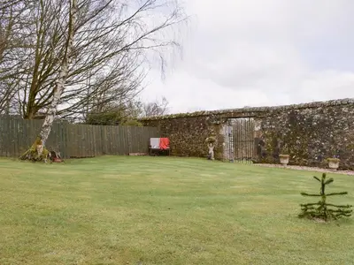a yard with a stone wall and a fence at Nether Cottage in Saline