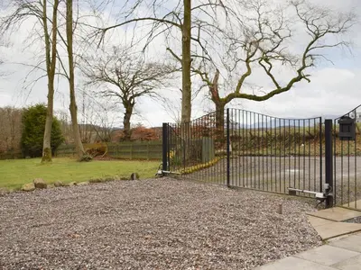 a black gate in a park with trees and grass at Nether Cottage in Saline