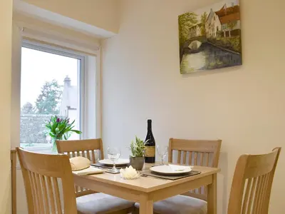 a dining room table with four chairs and a window at Kinneddar Cottage in Saline