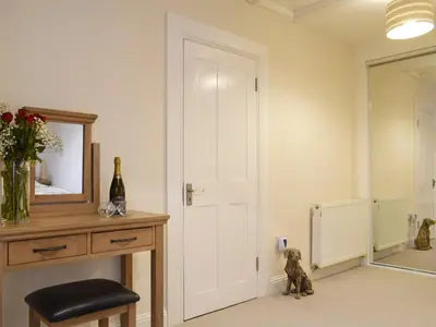a room with a white door and a table with a mirror at Kinneddar Cottage in Saline