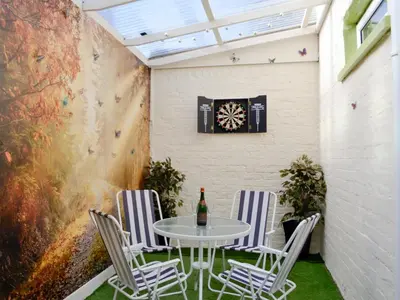 a patio with a table and chairs and a dartboard on the wall at Park View Cottage in Stranraer