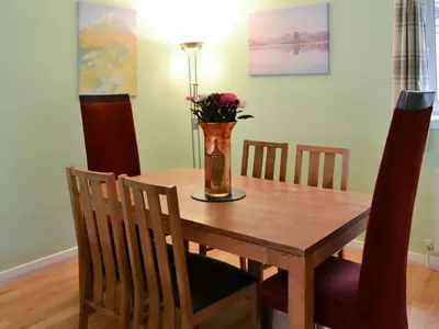 a dining room table with a vase with flowers in it at Harbour View in Oban