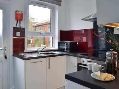 a kitchen with white cabinets and a black counter top at Rocky Mountain View in Ballachulish