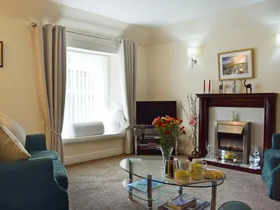 a living room with a table and a fireplace at Caroch Cottage in Comrie