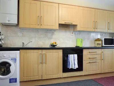 a kitchen with wooden cabinets and a dishwasher at Caroch Cottage in Comrie