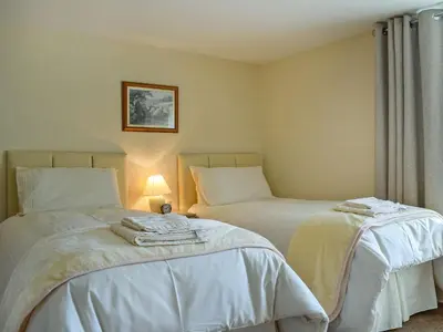 a bedroom with two beds and a lamp in it at Caroch Cottage in Comrie