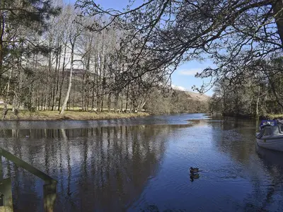 a boat on a river with a duck in the water at Casa Duran in Killin