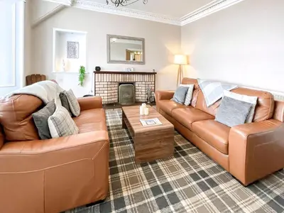 a living room with two couches and a fireplace at Thornbank in Millport