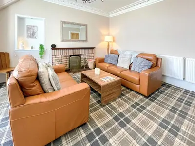 a living room with two couches and a fireplace at Thornbank in Millport