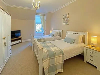 a bedroom with two beds and a television in it at Thornbank in Millport