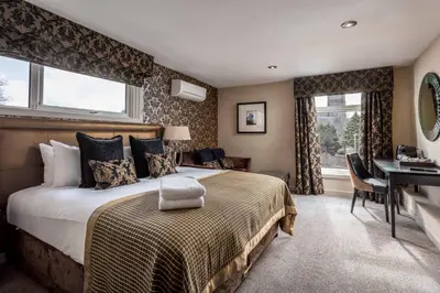 a bedroom with a bed and a desk and windows at The Kylestrome in Ayr