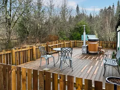 a wooden deck with two chairs and a table on it at Bonnie's Bothy in Port of Menteith