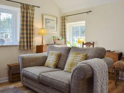 a living room with a couch and two pillows at Bonnie's Bothy in Port of Menteith