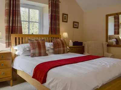 a bedroom with a large bed and a mirror at Bonnie's Bothy in Port of Menteith