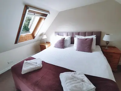 a bedroom with a large white bed with a window at The Old Dairy in Brodick