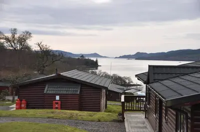 a group of buildings with a lake in the background at West Loch Shores in Tarbert