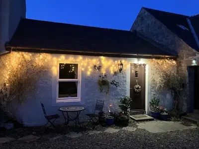a house with lights on the side of it at night at Midkinleith Farm Holiday Cottage in Edinburgh