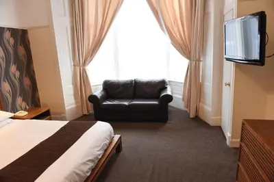 a room with a bed and a chair and a television at Sandyford Hotel in Glasgow