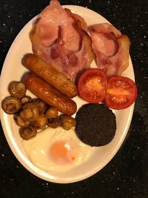 a plate of food with eggs sausage tomatoes and beans at The Moorings in Tarbert