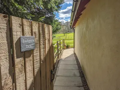 a sign on the side of a fence next to a sidewalk at Badgers Den in Linlithgow