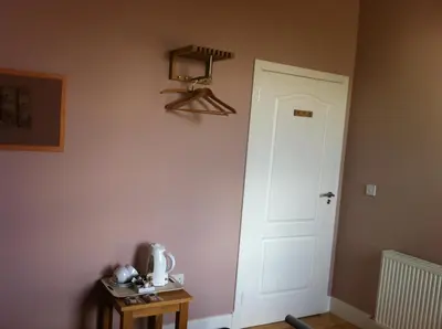 a room with a white door and a table with a lamp at Ashbank Bed & Breakfast in Drymen
