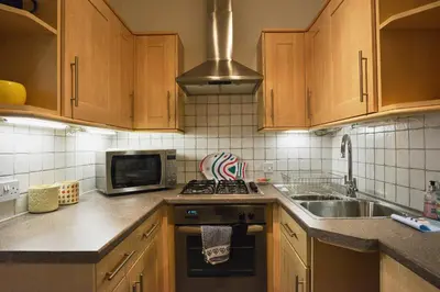 a kitchen with wooden cabinets and a sink and a microwave at Comely Bank Apartment in Edinburgh