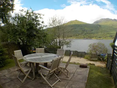 a table and chairs with a view of a lake at 16 Admiralty in Arrochar