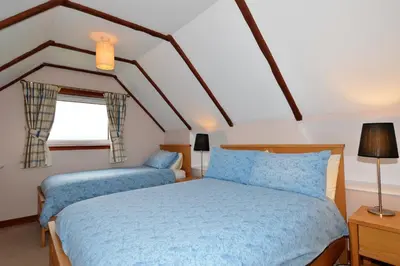 a bedroom with two beds and a window at Rowan Cottage in Blairmore