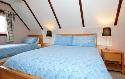 a bedroom with two blue beds and two lamps at Rowan Cottage in Blairmore
