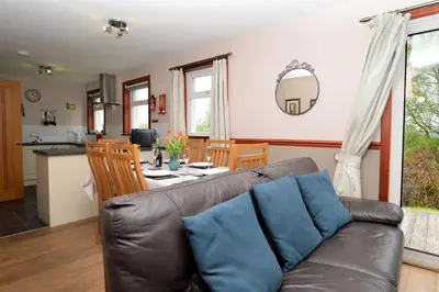 a living room and kitchen with a couch and a table at Rowan Cottage in Blairmore